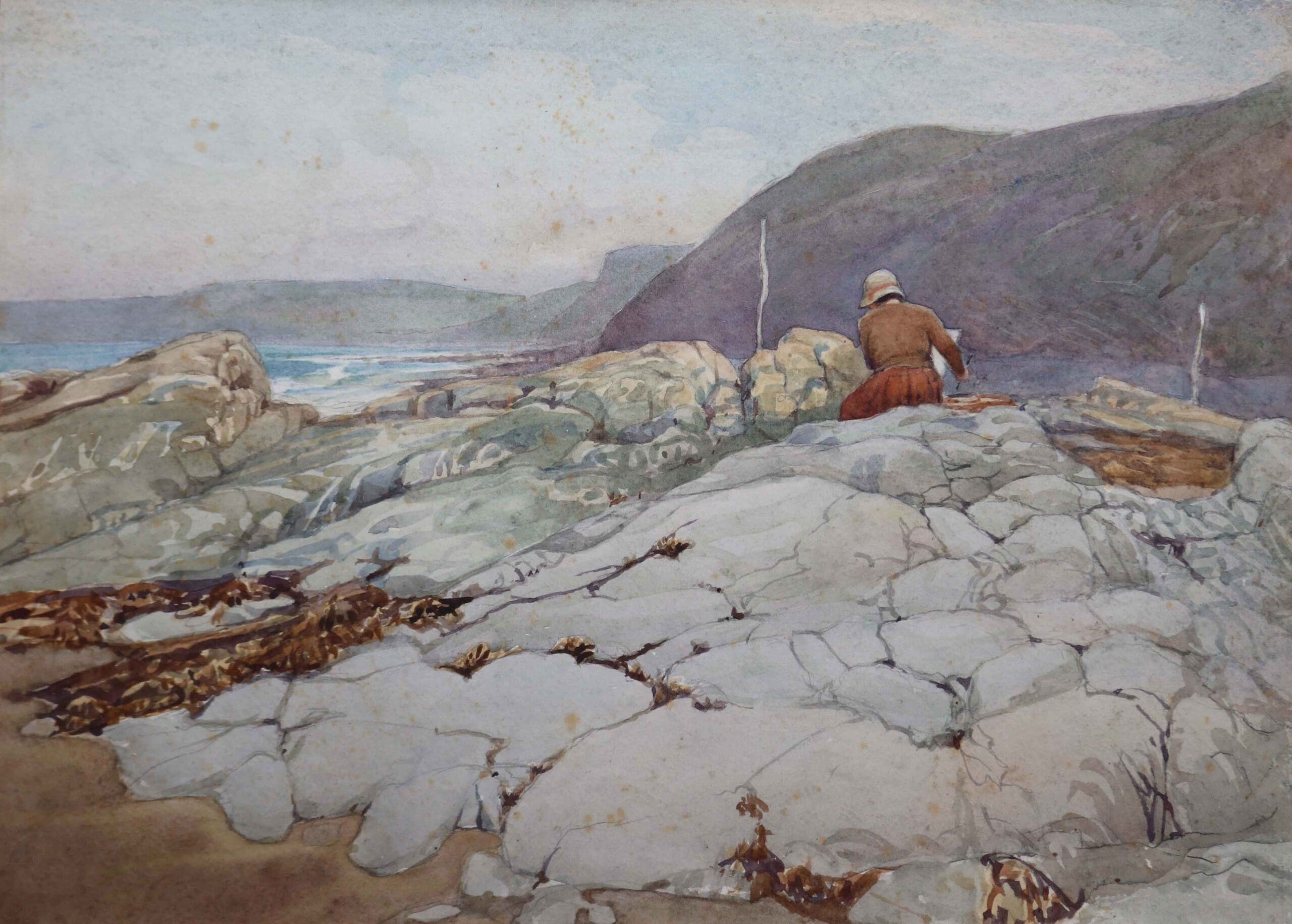 Judith Ackland's watercolour of a woman sat on the rocks at Bucks Mills